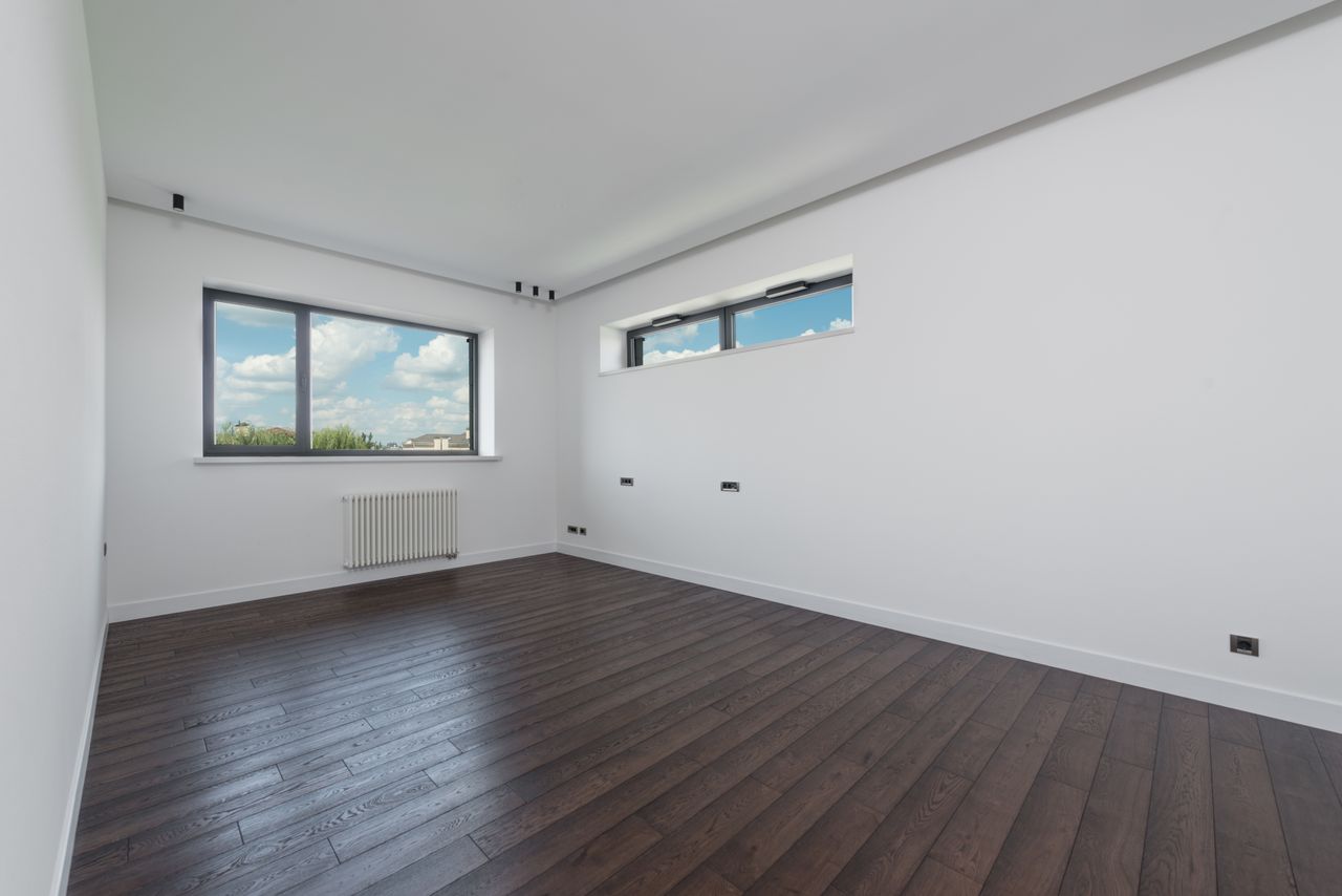core-values Interior of empty spacious room with laminated floor big windows white walls and ceiling in daylight